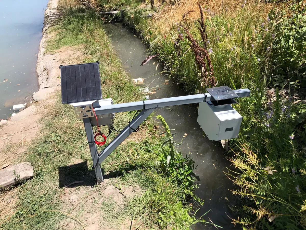 Equipo de medición con panel solar instalado junto a una acequia