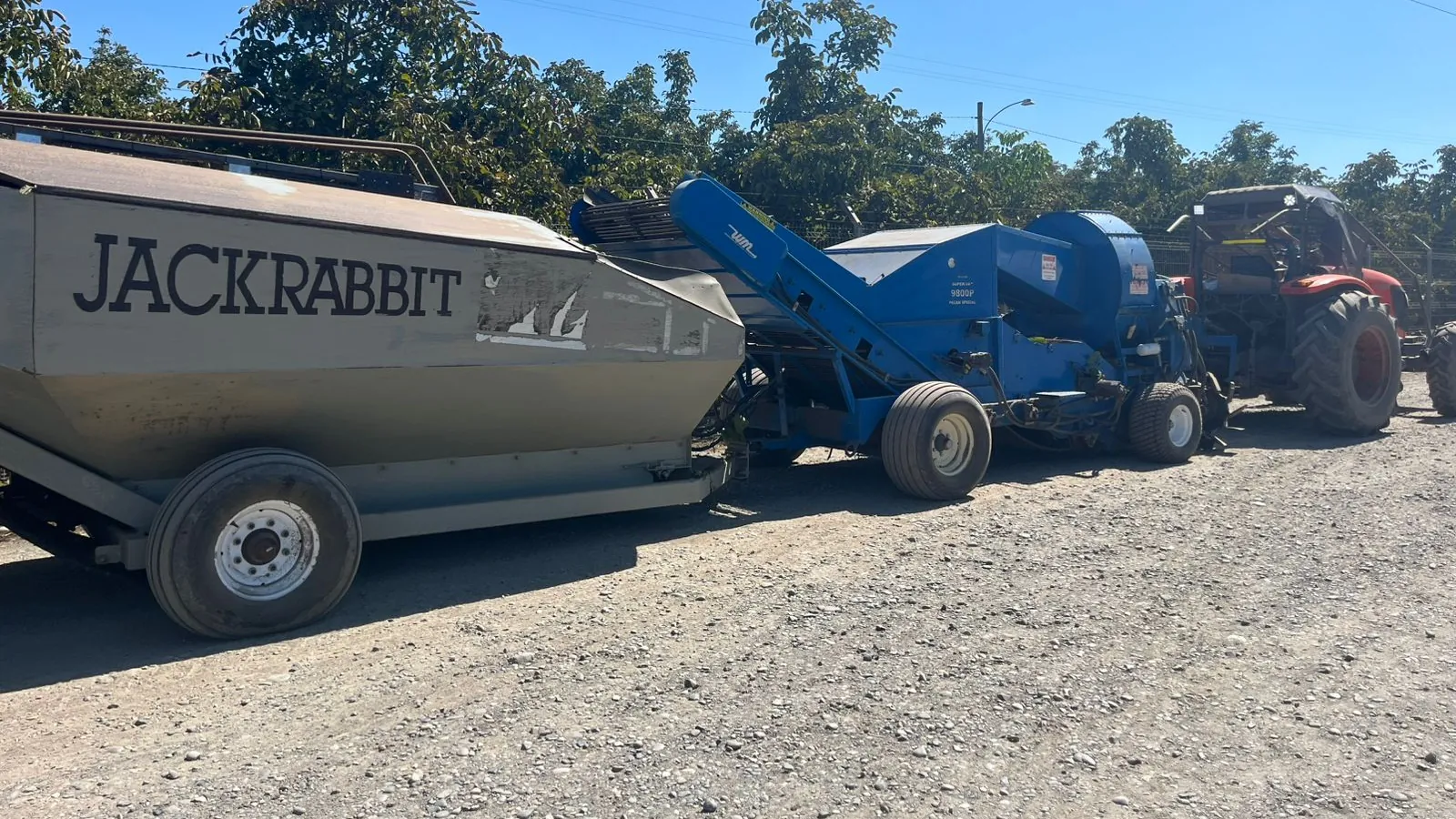 Cosechadora y carros de cosecha de nueces en un camino del huerto