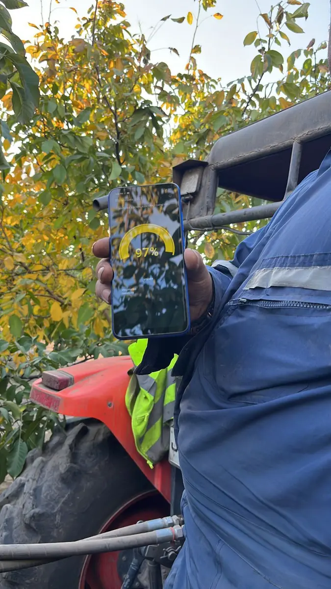 Celular en la cabina de una cosechadora mostrando el porcentaje de llenado de tolva