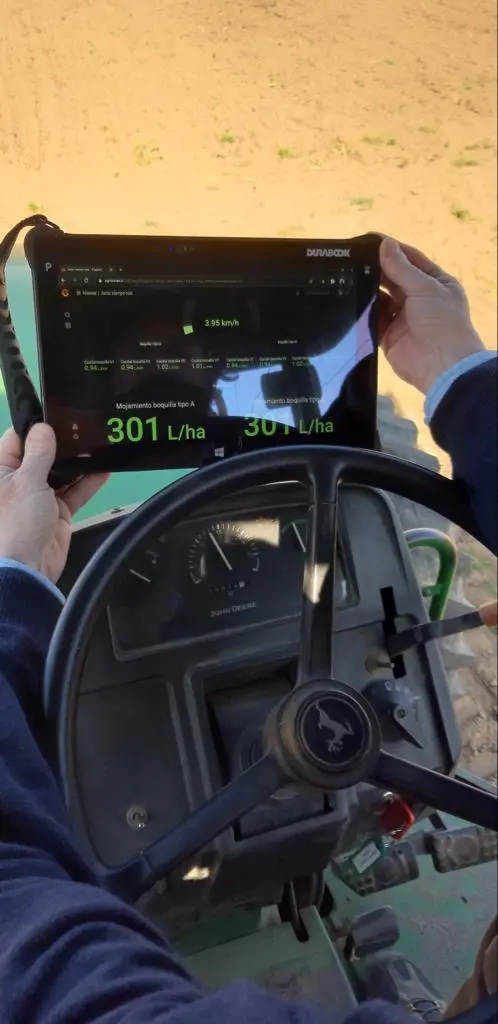 Operador con una tablet en la cabina del tractor mostrando el mojamiento en vivo